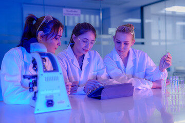 A diverse group of female science students works together on a lab experiment. They are using a...
