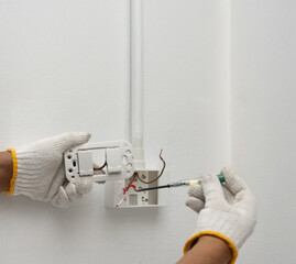 Close-up of Electrician Testing Live Wire with Voltage Tester or Detection Screwdriver Before Wall Switch Installation.