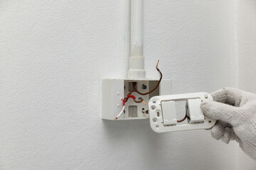 Close-up of Electrician Compare New Switch with Box Before Wall Switch Installation.