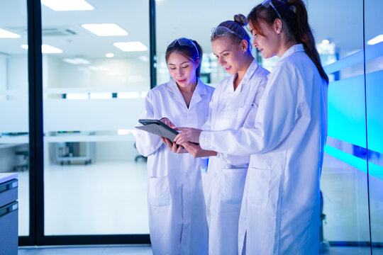 A diverse team of researchers in a biotechnology lab reviews preliminary data from an experiment on a tablet. They are collaborating on the next phase of their R&D project.
