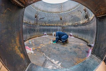 Top view male climbs up the stairs into the tank stainless chemical area inside
