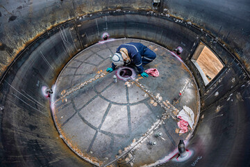 Top view male climbs up the stairs into the tank stainless chemical area inside