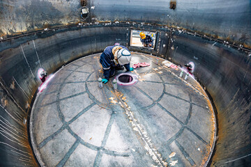 Top view male climbs up the stairs into the tank stainless chemical area inside