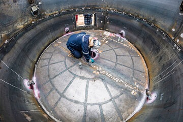 Top view male climbs up the stairs into the tank stainless chemical area inside