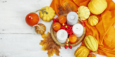 Autumn cozy composition. Pumpkins in a basket, candles, cones, seeds. Traditional fall decor