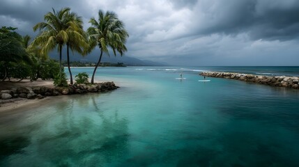 Fototapeta premium Turquoise tropical waters with palm trees and paddleboarders glide under a dramatic cloudy sky conveying a serene yet atmospheric seascape