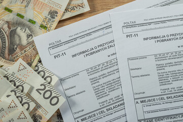 Polish PIT-11 tax form with 200 zloty banknotes, personal income tax and finance concept in Poland