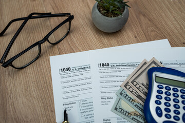 Form 1040 with US dollar bills, glasses and calculator for 2025 tax filing