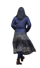 jeune femme qui marche, vue de dos, portant une veste matelassée bleue et une jupe longue bohème de style gitane à motifs floraux, collants bleu marine et bottines marron, photo détourée, fond blanc
