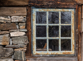 This scene features a rustic cabin window made of wood and glass, surrounded by a stone wall. The...