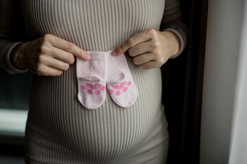 Pregnant woman holding baby socks on belly