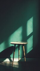 Small round table with wooden legs standing against a green wall with shadows