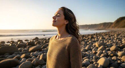 Woman enjoying the sun on a rocky beach with her eyes closed and smiling