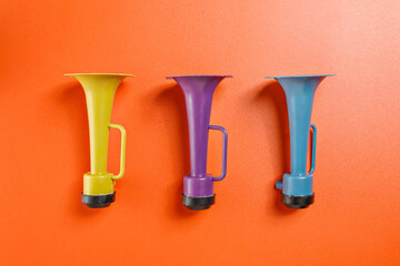 Plastic horn on a red background. Concept of a party or a holiday celebration