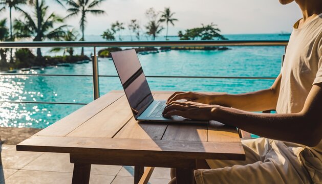 Digital nomad lifestyle: A person working on a laptop at a wooden table on a sunny terrace overlooking a tropical pool and palm trees.