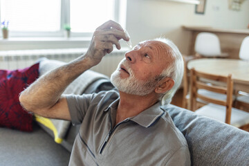 Eye drops, senior man with medical, healthcare and wellness pharmaceuticals. Senior male with dry...
