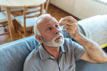 Eye drops, senior man with medical, healthcare and wellness pharmaceuticals. Senior male with dry...