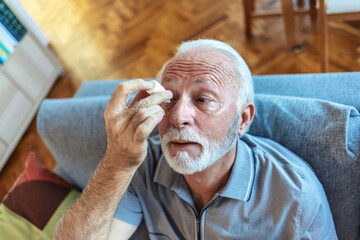 Man putting liquid drops in his eye solving vision problem.Senior dropping eye drop medicine...