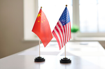 Flags signal negotiation meeting at conference table. Miniature China and USA flags stand together...