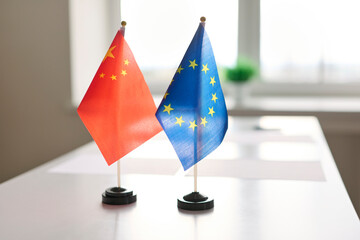 Flags on meeting table signal diplomacy and negotiation. China and European Union desk banners...