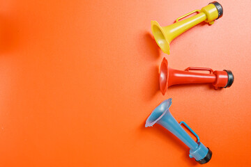 Plastic horn on a red background. Concept of a party or a holiday celebration