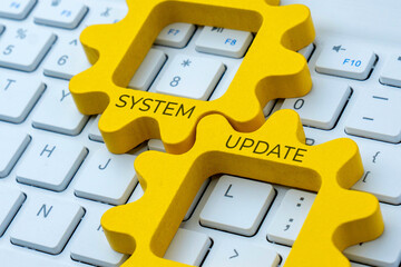Two interlocking gear with text SYSTEM UPDATE on a computer keyboard. Improvement, maintenance, or software upgrade concept.