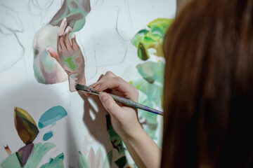 Close-up of an artist’s hand painting a portrait on canvas, adding fine details with a brush. Creative process, art studio atmosphere, and delicate craftsmanship.
