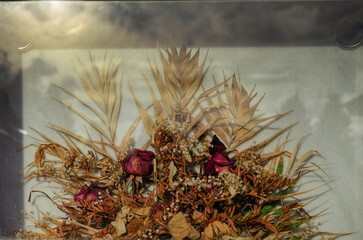 Bouquet of flowers is preserved dried behind the glass of a tomb