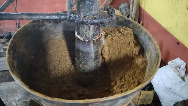 Close-up of Traditional Oil Mill Expeller Grinding Brown Seeds or Spices into Powder or Cake