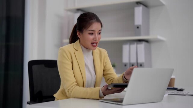 Asian adult woman working from home office managing finances documents laptop computer calculating taxes business planning remote work strategy professional productivity