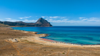 Aerial view of Macari Beach, located near San Vito Lo Capo in Sicily, Italy. In the background is a mountain called Monte Cofano, and the turquoise sea in the foreground.