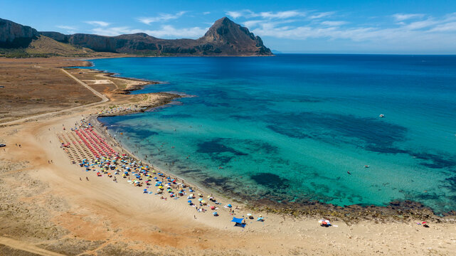 Aerial view of Macari Beach, located near San Vito Lo Capo in Sicily, Italy. In the background is a mountain called Monte Cofano, and the turquoise sea in the foreground.