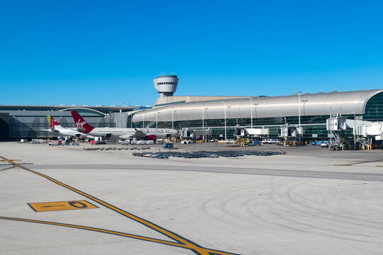 The modern architecture of the Miami International Airport (MIA) terminal, with a waiting passenger jet and the iconic control tower.