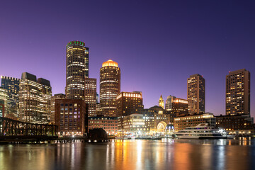 Naklejka premium The stunning Boston downtown skyline at twilight, viewed from the Seaport, with reflections on the calm water.