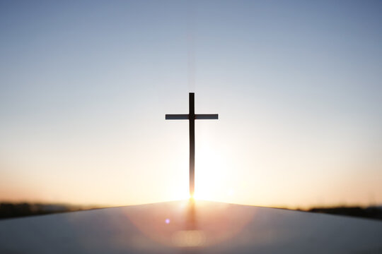 Rising New Year sunrise and the Holy Cross of Jesus Christ, with bright sky and shining sun in the background
