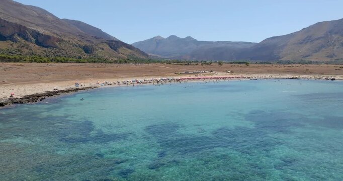 Aerial view of Macari Beach, located near San Vito Lo Capo, in province of Trapani, in Sicily, Italy. In the background is a mountain and the turquoise sea in the foreground.