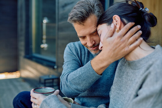 Mature couple embracing lovingly, finding comfort and connection during a quiet moment together on a porch - Powered by Adobe