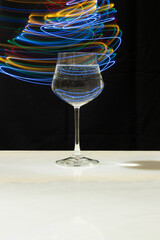 Wine glass with water and neon light on marble table and black background