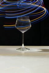 Wine glass with water and neon light on marble table and black background