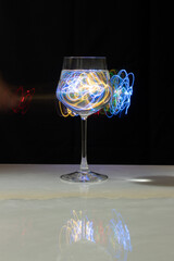 Wine glass with water and neon light on marble table and black background