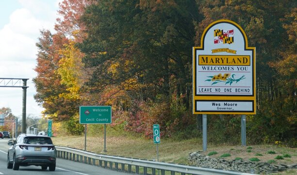 Cecil County, Maryland, U.S - Oct 25, 2025 - Maryland state line welcome sign featuring the 'Leave No One Behind' motto, set against a backdrop of autumn foliage.