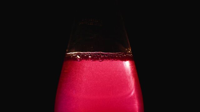 A rich ruby red beverage in glass flask illuminated against dark background for elegant presentation
