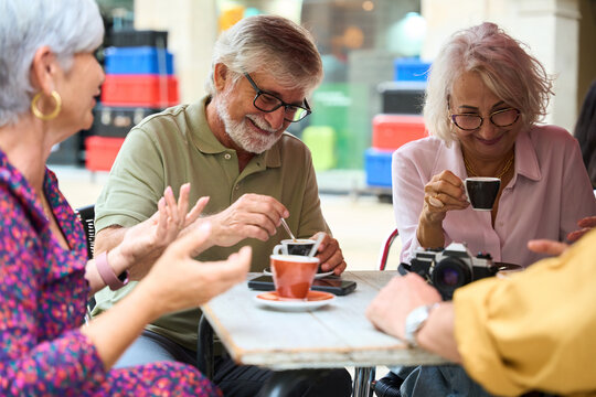 Senior friends enjoying coffee and conversation in cafe