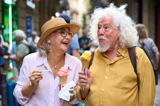 Senior couple enjoying ice cream laughing during vacation