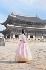 A woman dressed in traditional attire standing in front of a grand building