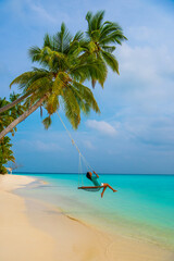 Tranquil closeup calm sea water waves with palm trees. Woman tourist swinging, Tropical island beach landscape exotic shore coast. Summer vacation, holiday amazing nature. Relax paradise, Maldives.