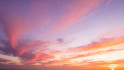 Fototapeta premium Wispy clouds paint the sky with vibrant sunset hues of pink and purple.