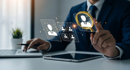 Businessman in suit uses a magnifying glass to select a candidate from a virtual selection panel on a table with tablet and laptop.