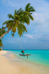 Tranquil closeup calm sea water waves with palm trees. Woman tourist swinging, Tropical island beach landscape exotic shore coast. Summer vacation, holiday amazing nature. Relax paradise, Maldives.