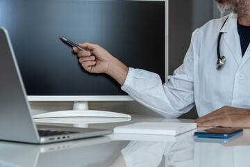 Experienced doctor actively pointing at a blank monitor screen, preparing for a digital presentation or consultation